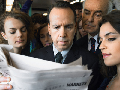 Commuters Reading Businessman's Newspaper on Train